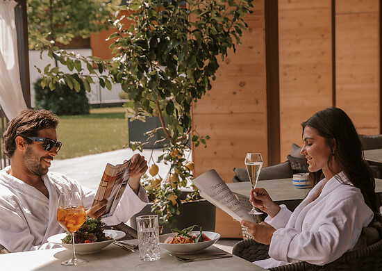 Paar sitzt im Bademantel bei Dolce Vita Flair und Essen im Garten des Hotels im Großarltal