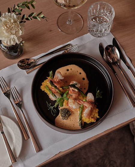Black plate with shrimp risotto on a wooden table