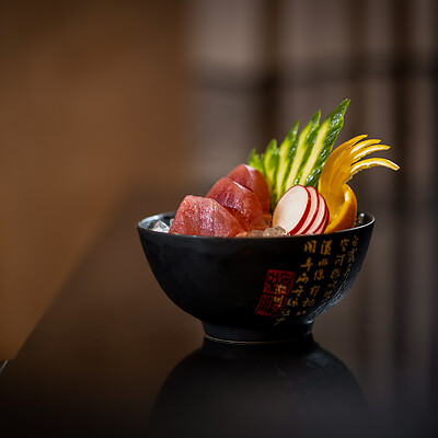 Asian sushi bowl on black plate with decoration