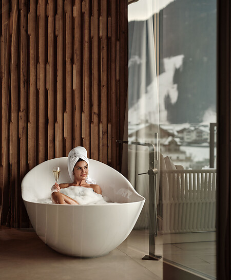 Woman lays in a bathtub of a spa suite