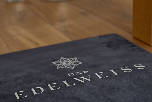 Matte mit dem Schriftzug "DAS EDELWEISS" auf einem Holzboden.